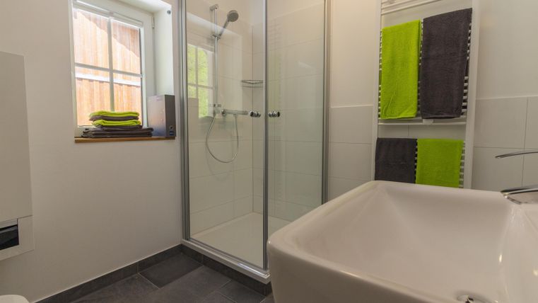 Une salle de bain moderne avec une douche et une baignoire blanche.
Des serviettes fraîches de couleurs vives sont accrochées de manière ordonnée.