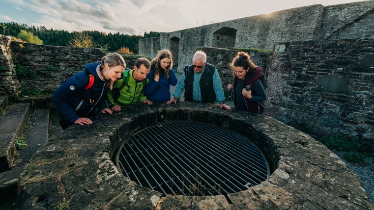 Groupe de personnes regardant dans un puits au château de Reifferscheid.