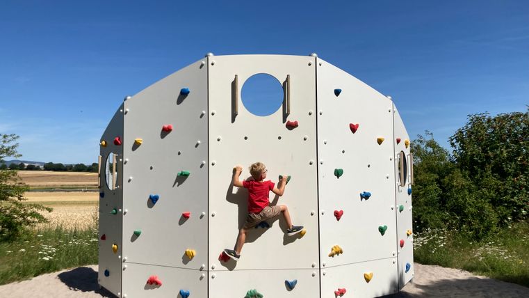 Ein Kind klettert an einer Kletterwand.