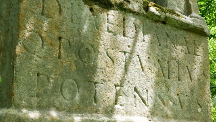 Gros plan sur une inscription antique sur un monument en pierre dans la forêt.