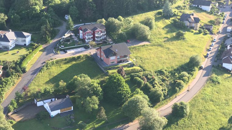 Een landelijke omgeving met meerdere huizen en groene weilanden. Het landschap wordt omringd door bomen en paden.