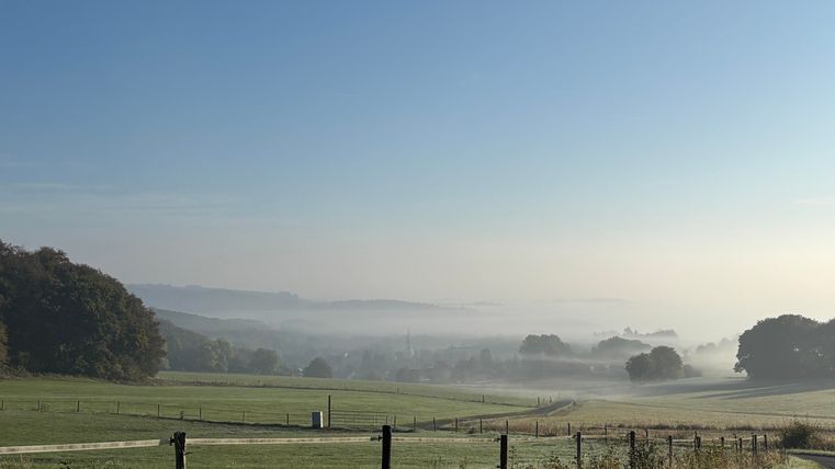 A picturesque landscape with gentle hills and morning fog. The clear sky gives the scene a peaceful atmosphere.