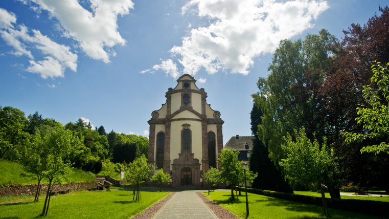 Vooraanzicht van het Himmerod klooster met blauwe lucht en groene omgeving.