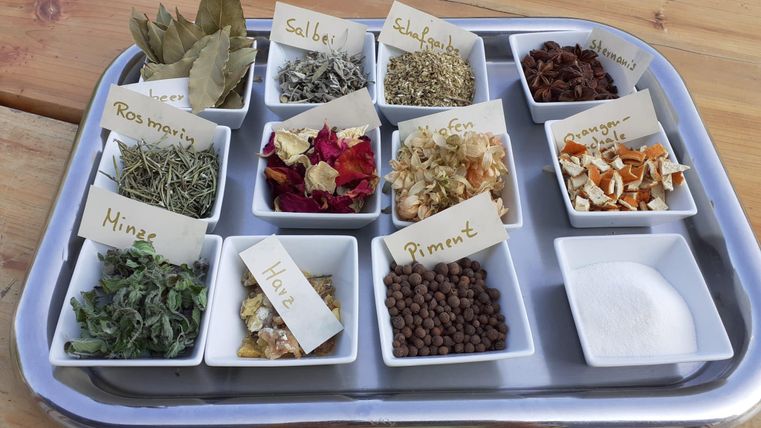 A selection of spices and herbs in small bowls on a tray. Each spice is labeled with a tagged label.