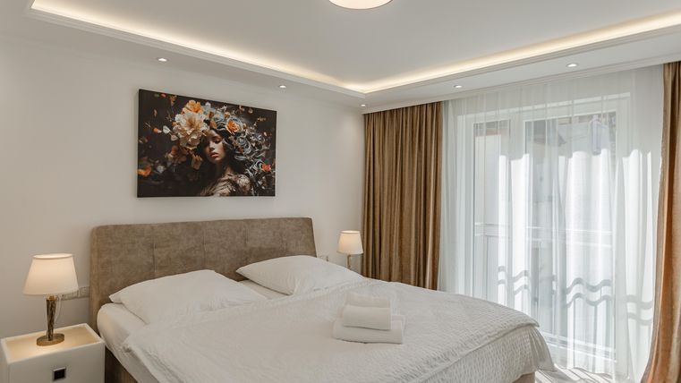 A modern bedroom with a large bed and stylish wall art. Large windows let in plenty of light and create a cozy atmosphere.