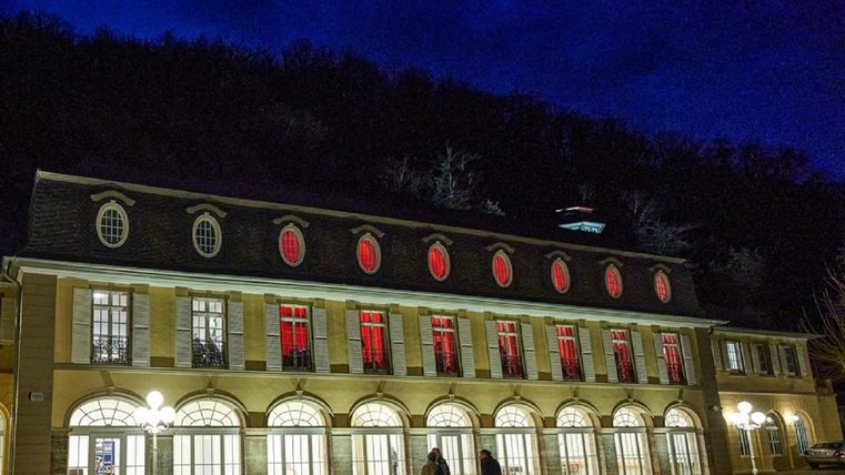 A historic building at night with red windows and a dark background. The scene is illuminated by the warm light of the street lamps.