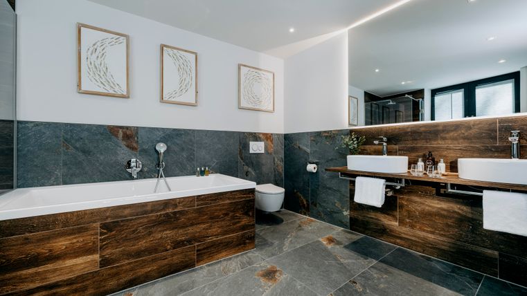 Une salle de bain moderne avec une baignoire et deux lavabos. Les murs sont de couleurs neutres et il y a des images décoratives.