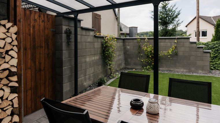 S'asseoir dehors à l'abri et faire des grillades, même par temps de pluie. À gauche se trouve le bois de chauffage pour le poêle à bois du salon.