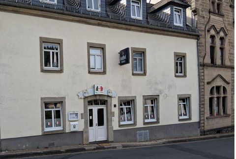 Un bâtiment confortable à deux étages avec une façade claire. La façade présente plusieurs fenêtres et une porte d'entrée, qui pourrait mener à un commerce ou à un établissement de restauration.