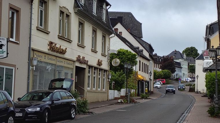 De Kurfürstenstraat met typische Duitse huizen en wat groen. De lucht is bewolkt, wat de scène een gezellige sfeer geeft.
