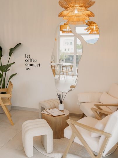 A stylish café with comfortable furniture and warm lighting accents. On the wall is the phrase: "let coffee connect us."
