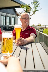 Mann genießt sein Bier im Biergarten mit Blick auf die Hocheifel
