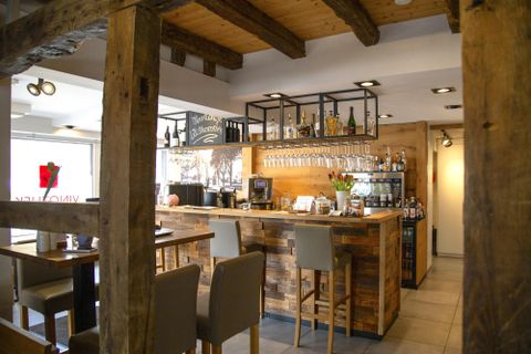 Een gezellige bar met een houten balie en moderne stoelen. De inrichting combineert rustieke charme met een uitnodigende sfeer.