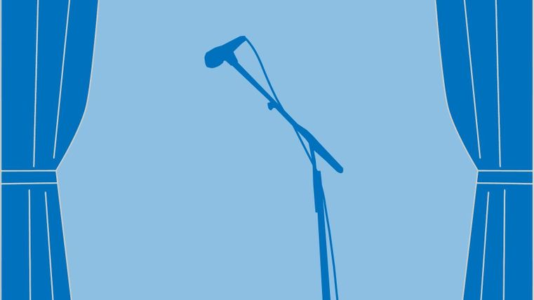 Een microfoon staat op een podium, omringd door blauwe gordijnen. De scène straalt een verwachtingsvolle sfeer uit voor een voorstelling.