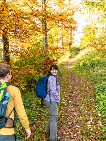 Ein Mann und eine Frau wandern durch herbstlichen Wald.