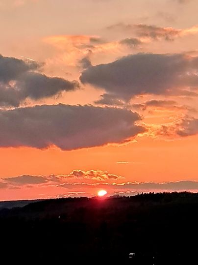 Een prachtige zonsondergang boven de heuvels met stralende oranje- en rottinten. Wolken trekken langzaam langs de lucht.