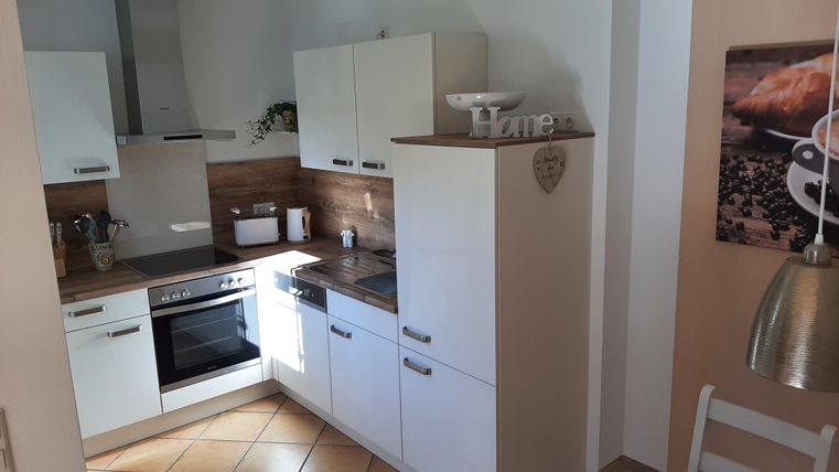 Eine moderne Küche mit weißen Schränken und Holzdetails. Auf der Arbeitsfläche befindet sich ein Herd und eine Spüle.