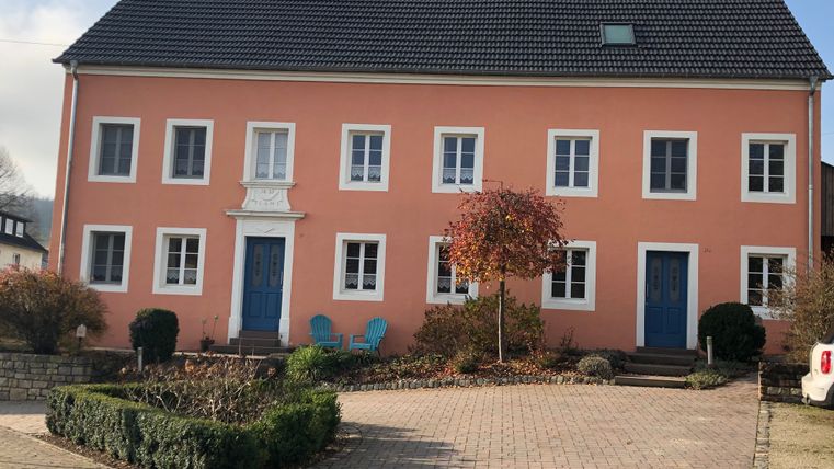 Oude boerderij met roze gevel en blauwe deuren in Oberweis.