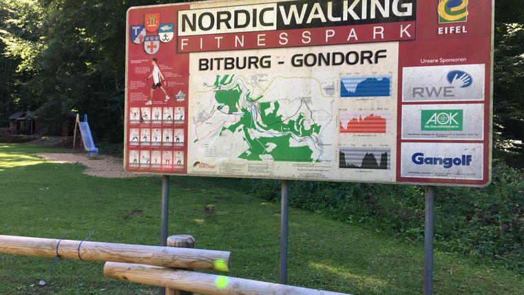 Schild des Nordic Walking Fitnessparks Bitburg-Gondorf im Wald.