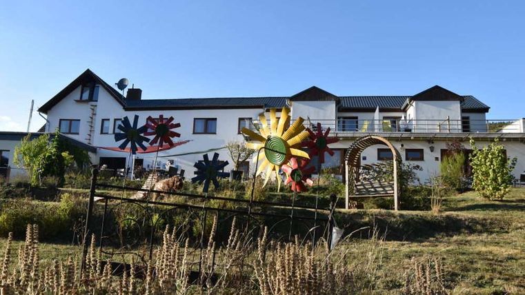 A large residential house with colorful wind turbines in the foreground. The garden is green and well-kept, ideal for relaxed days outdoors.