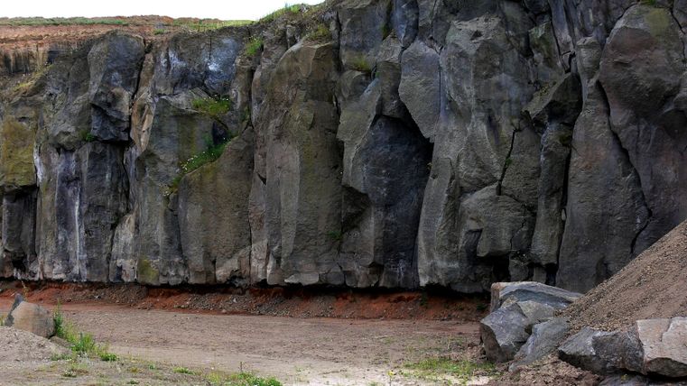 Steengroeve met hoge rotswanden en vegetatie.