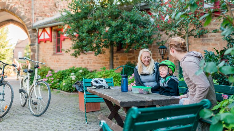 Gezin zittend aan een houten tafel op de binnenplaats van Kasteel Satzvey.