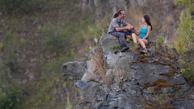 Twee mensen zitten op een rots in een steengroeve en praten.