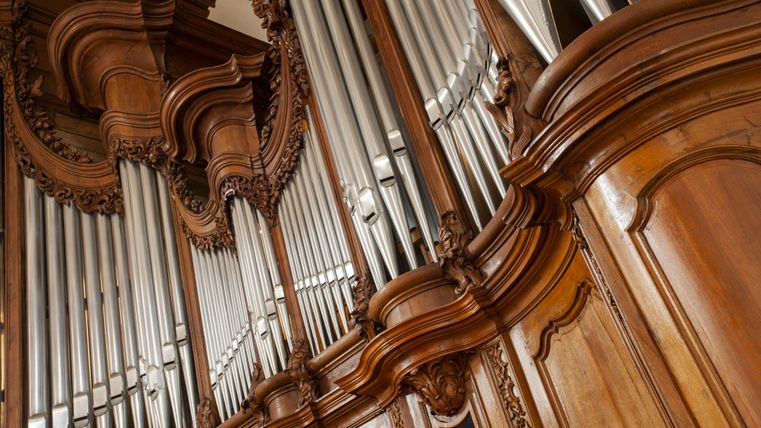 Un impressionnant orgue avec des ornements en bois raffinés et des tuyaux en argent. L'image montre la vue détaillée de l'instrument.