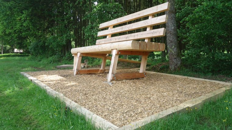 Grand banc en bois dans la forêt sur une place de copeaux de bois.