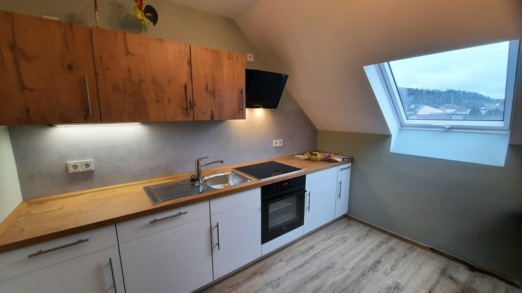 Une cuisine moderne avec des meubles en bois et blancs. La fenêtre offre une vue sur le paysage.