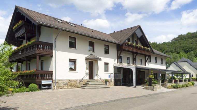 A modern building with multiple floors and balconies. Surrounded by trees and a clear sky.