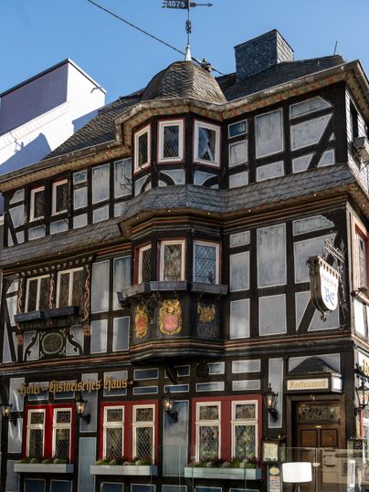 Vakwerkhuis Blaue Ecke in Adenau met decoratieve elementen en uithangborden.