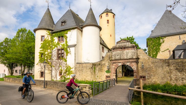 Zwei Radfahrer fahren an der Burg Rittersdorf vorbei.