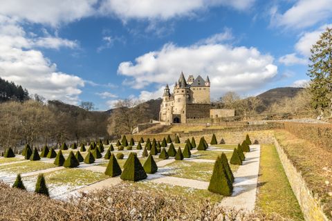 Kasteel Bürresheim met verzorgde tuin en blauwe lucht op de achtergrond.