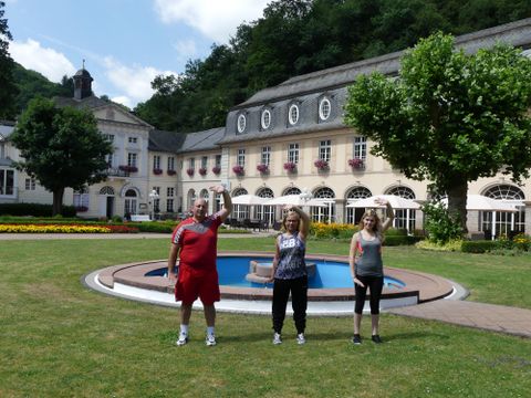 Eine Frau geht auf einem schmalen Pfad, umgeben von dichtem Grün. Die Bäume bilden einen natürlichen Bogen über dem Weg.