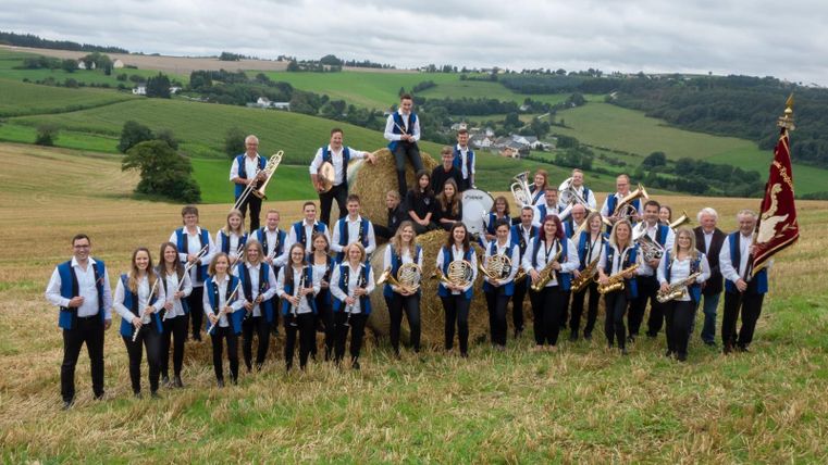 Ein Plakat für ein Adventskonzert des Musikvereins "Harmonie" Ringhuscheid. Es zeigt die Gruppe in festlicher Kleidung vor einer ländlichen Kulisse mit einem Datum und Veranstaltungsort.