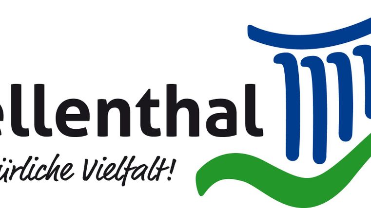 Ein Logo von Hellenthal mit dem Slogan „... natürliche Vielfalt!“ Es zeigt stilisierte Säulen, eine Sonne und einen grünen Schwung.
