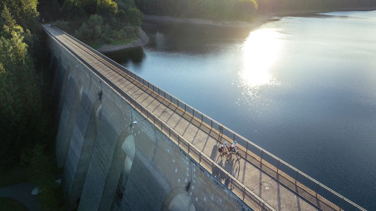 Vue aérienne du barrage d'Oleftal à Hellenthal avec des cyclistes sur le mur du barrage.