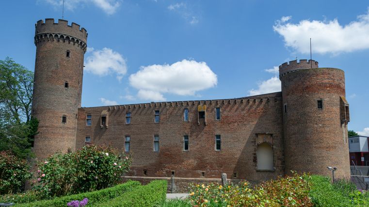 Zülpich Castle with two round towers and garden in the foreground.