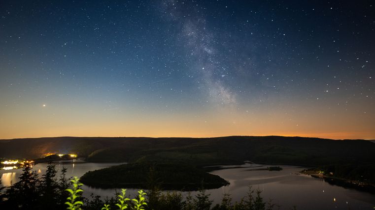 ein dunkles Bild, dass Sterne zeigt, darunter ein See