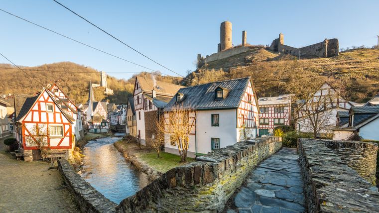 Vakwerkhuizen in Monreal met kasteelruïnes op de achtergrond.