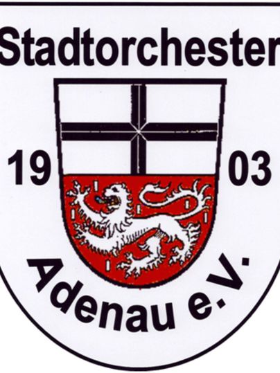 Das Bild zeigt ein Wappen mit der Aufschrift "Stadtorchester Adenau e.V." und einem roten Hintergrund mit einem Drachen. Das Wappen enthält auch ein Kreuz und das Gründungsjahr 1903.