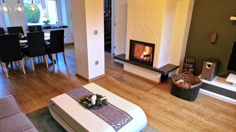 A cozy living room with a modern fireplace and a bright, inviting atmosphere. The table is festively decorated and there is a view of the dining area.
