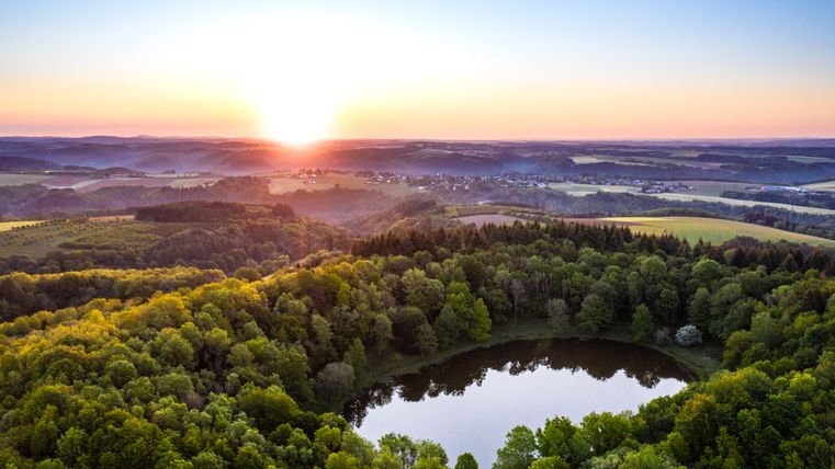 Aerial view of the Windsborn crater with lake and sunrise in the background.