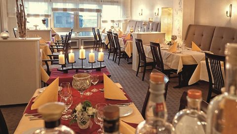 An elegant restaurant with a cozy atmosphere. Tables are decorated with red and yellow tablecloths as well as candles.