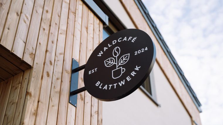 A sign of the forest café "Blattwerk" with a modern design. The café was founded in 2024 and features a natural, welcoming atmosphere.