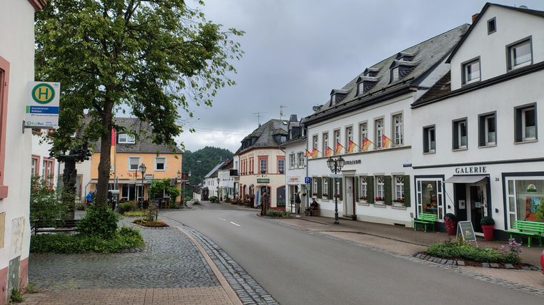 De Kurfürstenstraße van Manderscheid, met goed bewaarde gebouwen. Bomen en een halte passen zich aan in de charmante omgeving.