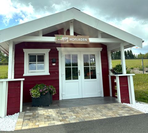 Een rood houten huis met een wit dak en een uitnodigende voordeur. Voor het huis staan planten in potten en het gebied is onderhouden.