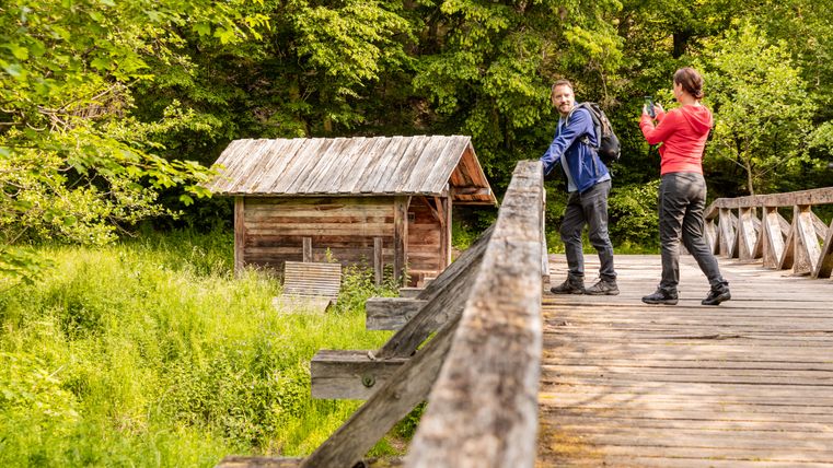Twee mensen op een houten brug voor een houten hut op het platteland.