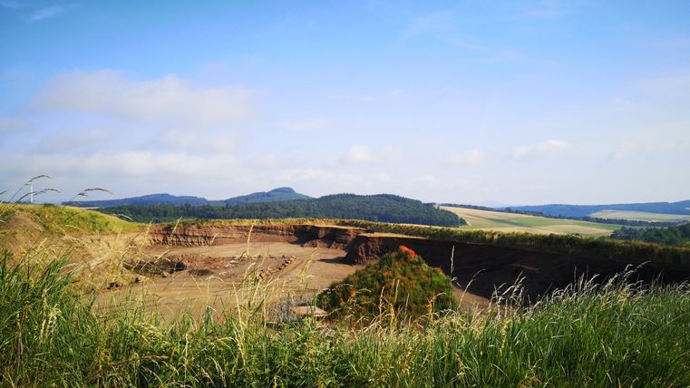 Landscape with hills and grasses in the foreground, blue sky.